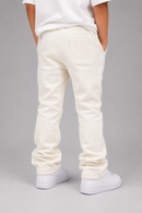 A person shown from the back wearing off-white or cream sweatpants with a white t-shirt and white sneakers, standing against a neutral gray studio background.