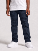 A person wearing dark navy distressed jeans with a white t-shirt and white sneakers, shown from the waist down against a light gray studio background.