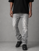 A person wearing light gray washed denim jeans, a black t-shirt, and black sneakers, standing against a textured gray studio background.