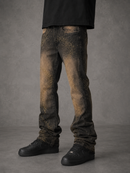 A person wearing slim-fit black jeans with a distressed gold glitter wash and black sneakers, shown from the waist down against a gray studio background.