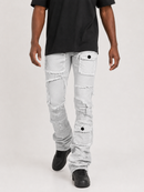 A person wearing light gray heavily distressed denim jeans with ripped details and buttoned cargo pockets, paired with a black t-shirt and black sneakers, shown from the waist down on a light gray studio background.