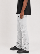 A person wearing light gray distressed denim jeans with frayed details and cargo pockets, paired with a black t-shirt and black sneakers, shown from the waist down against a light gray studio background.