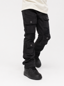 Black cargo pants with multiple flap pockets and button details, shown on a model from the waist down wearing a cream t-shirt and black sneakers against a white studio background.