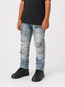 A child wearing light-wash blue distressed cargo jeans with frayed details, a black t-shirt, and black sneakers, standing against a light gray studio background.