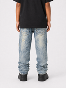 Rear view of a person wearing light-wash blue distressed jeans with a black t-shirt and black shoes, photographed against a light gray studio background.