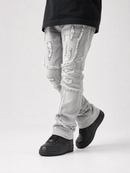 Light gray distressed skinny jeans with ripped details and frayed edges, shown on a model wearing black platform sneakers against a light gray studio background.