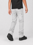 A person shown from the back wearing light gray washed denim jeans with distressed details, a black t-shirt, and black sneakers, against a light gray studio background.