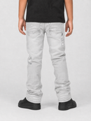 A person shown from the back wearing light gray distressed jeans, a black t-shirt, and black shoes against a light gray studio background.