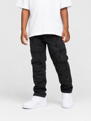 A child wearing black distressed cargo-style jeans with ripped details, paired with a white t-shirt and white sneakers, shown from the waist down on a light gray studio background.