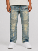 A kid wearing light blue distressed denim jeans with faded wash details, shown from the waist down against a light gray studio background. The person is also wearing a cream t-shirt and white sneakers.