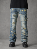 Distressed light blue denim jeans with heavy fading, rips, and frayed detailing, shown on a model from the waist down against a gray studio background.