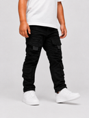 A child wearing black cargo pants with multiple flap pockets, styled with a white t-shirt and white sneakers against a light gray studio background.