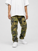 A person wearing camouflage cargo pants with a white oversized t-shirt and white sneakers, shown from the chest down against a light gray studio background.