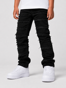 A person wearing black distressed jeans with frayed cut details running horizontally down the legs, paired with a white t-shirt and white sneakers, shown from the waist down on a light gray studio background.