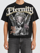 A person wearing a black graphic T-shirt with a large angel illustration and the word 'Eternity' across the chest, paired with dark gray jeans against a light gray studio background. Fresh N Fitted