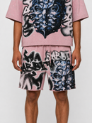 A model wearing a matching pink graphic t-shirt and shorts set. The set features a bold black, white, and blue graffiti-style face print with a subtle silver glitter texture, set against a plain light gray background. Rare Peace 'Mask' Rhinestone Shorts (Dust Pink) RS6004 T fresh N Fitted in Stockton California 
