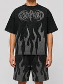 A model wearing a black acid-wash graphic t-shirt and matching shorts featuring a metallic silver flame pattern and a stylized logo on the chest, set against a plain light gray background. fresh n fitted Stockton 