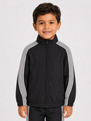 A young boy wearing a black zip-up track jacket with white stripes down the sleeves, standing against a light gray studio background.