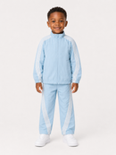 A young boy modeling a light blue tracksuit with white stripes down the sleeves and legs, paired with white sneakers, against a plain light gray background.