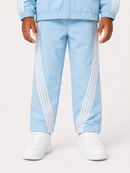A child wearing light blue track pants with white side stripes, a matching light blue zip-up jacket, and white sneakers, shown from the waist down against a plain light background.