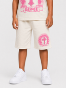 A child wearing off-white shorts with a pink graphic print on the left leg, paired with a matching graphic t-shirt and white sneakers, shown from the waist down against a light gray studio background.