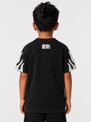 A child viewed from behind wearing a black washed short-sleeve t-shirt with a white graphic print on the upper back and white abstract patterns on both sleeves, set against a plain light gray background.