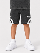 A child wearing washed black denim shorts with white flame and text graphics, styled with white sneakers and socks against a light gray studio background.