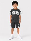A young boy modeling a dark gray acid-wash t-shirt and matching shorts set with white graphic details, paired with white sneakers, against a light gray studio background.