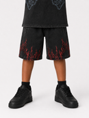 A person wearing black denim shorts with red flame embroidery, paired with black sneakers and black socks, shown from the waist down on a light gray studio background.