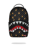 A SPRAYGROUND Shark backpack in black checkered canvas with a graphic of a shark mouth showing white and red teeth, and small orange and yellow fire logos scattered across the surface.