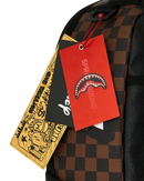 A SPRAYGROUND x M&F Disney backpack featuring a brown and black checkered pattern, a shark mouth graphic on the side, and a large front print of Mickey, Donald, Daisy, and Pluto wearing blue outfits under the text 'On Top of the World M&F Always Fresh'.