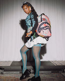 Person holding a colorful shark backpack with a plain background