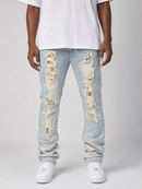 A person wearing light-wash distressed denim jeans with ripped details showing tan and off-white fabric underneath, paired with a white T-shirt and white sneakers, photographed against a light gray studio background.