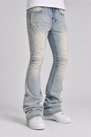Light-wash blue denim jeans with a faded, distressed look, shown on a model from the waist down wearing white sneakers against a light gray studio background.