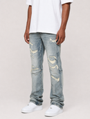 A person wearing light-wash blue distressed jeans with ripped details, paired with a white t-shirt and white sneakers, shown from the waist down against a light gray studio background.