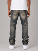 Rear view of a person wearing faded dark gray slim-fit jeans with a white t-shirt and white sneakers, standing against a light gray studio background.