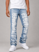 A person wearing light blue distressed jeans with large white vertical text graphics, paired with a white t-shirt and white sneakers, photographed against a neutral gray studio background.